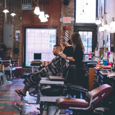 Far away shot of a female barber shaving a man's head