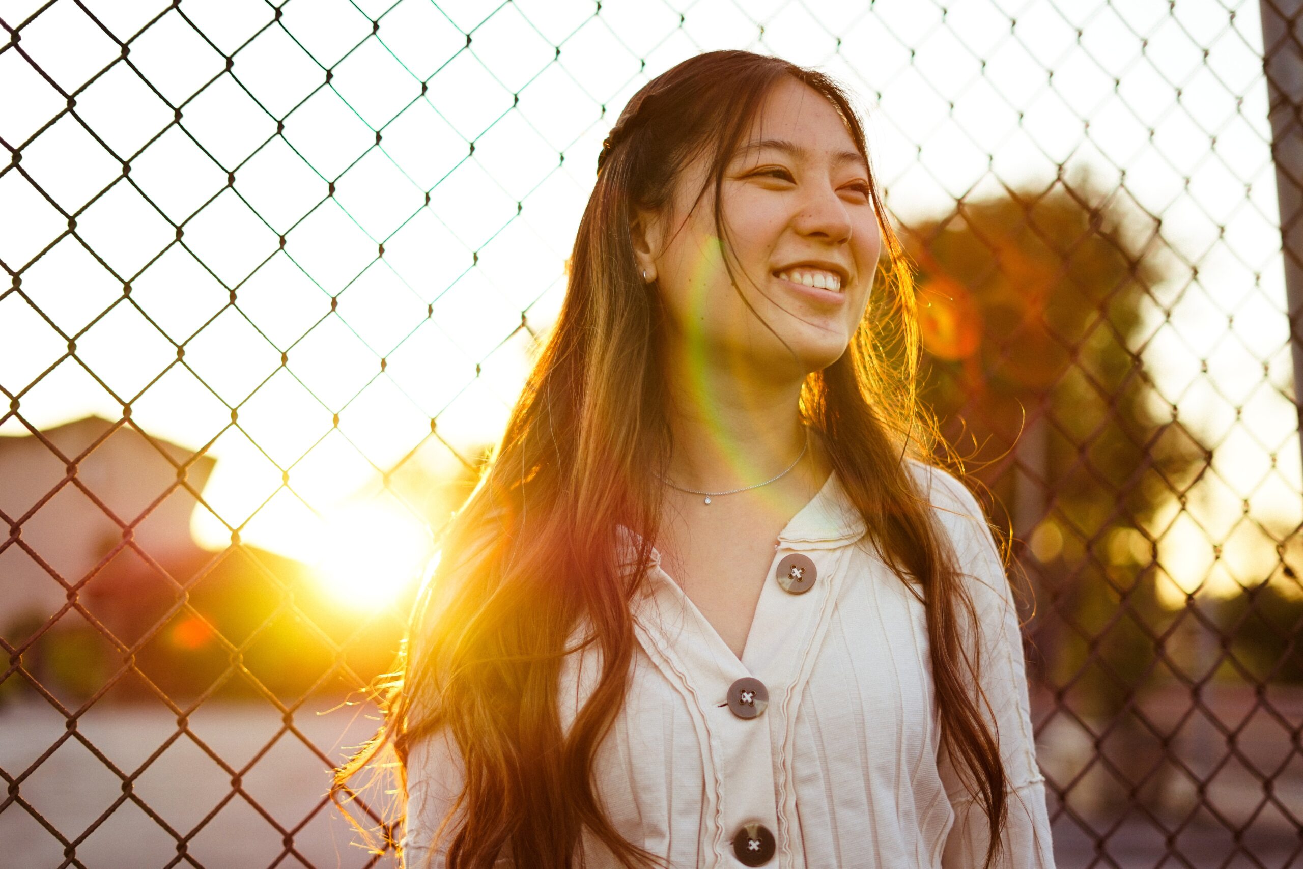 smiling woman leaning against a fence